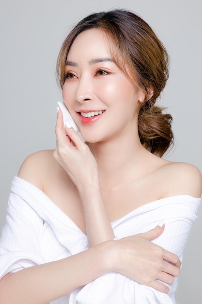 Femme asiatique avec un beau visage et une peau fraîche et propre parfaite Portrait de modèle féminin nettoyant son maquillage sur fond gris isolé Cosmétologie Soins du corps chirurgie plastique beauté et spa