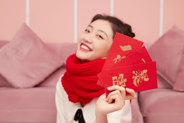 Une femme asiatique de beauté célèbre le paquet rouge du nouvel an chinois