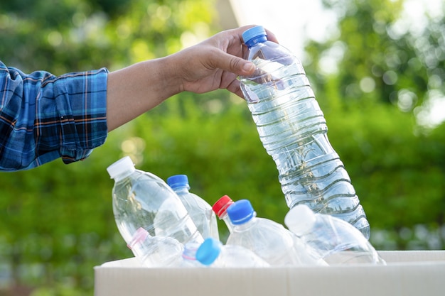 Une femme asiatique bénévole transporte des bouteilles d'eau en plastique dans une poubelle