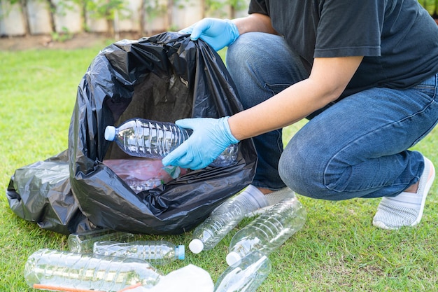 Une femme asiatique bénévole transporte des bouteilles d'eau en plastique dans des sacs à ordures dans le parc, recycle le concept d'écologie de l'environnement des déchets.