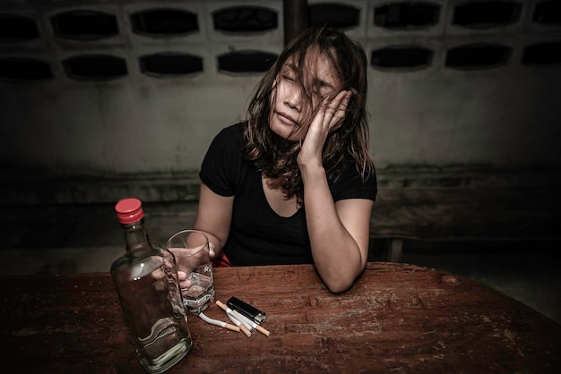 Une femme asiatique boit de la vodka seule à la maison la nuitThailand peopleStress femme ivre concept