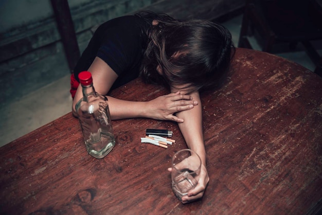 Une femme asiatique boit de la vodka seule à la maison la nuitThailand peopleStress femme ivre concept