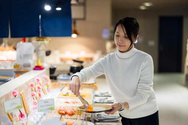 Une femme asiatique a un buffet au restaurant.