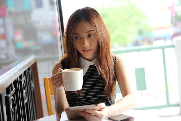 Femme asiatique buvant du café avec tablette