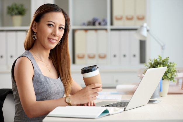 Femme asiatique avec café à emporter au bureau