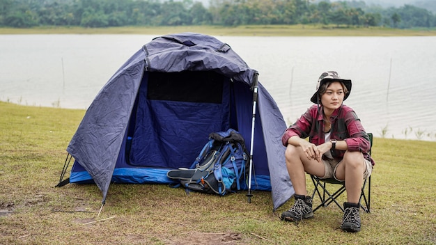 Femme asiatique camping au réservoir et asseoir dans une chaise