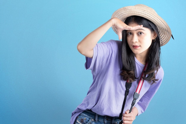 Femme asiatique avec chapeau et caméra regardant quelque chose avec un fond coloré