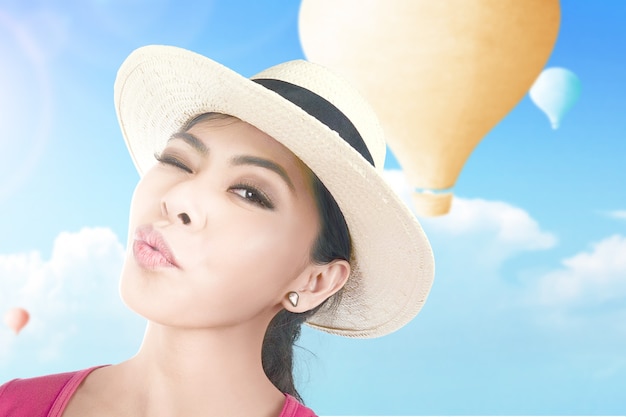 Femme asiatique avec un chapeau prenant un selfie avec un ballon à air coloré volant avec un fond de ciel bleu