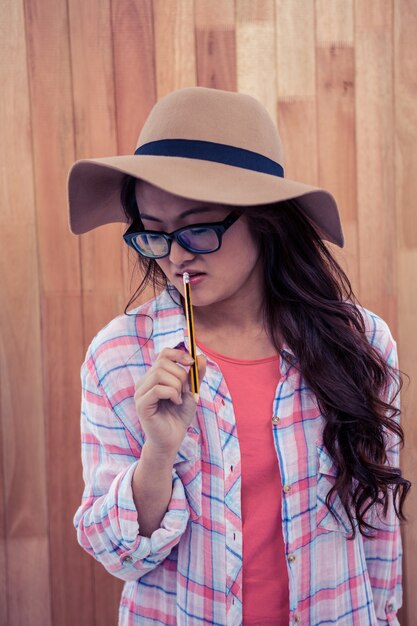 Femme asiatique, à, chapeau, tenue, crayon, contre, mur bois