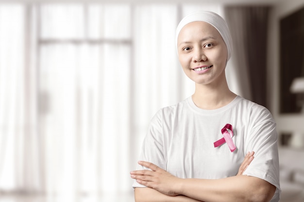 Femme asiatique en chemise blanche avec un ruban rose à la maison