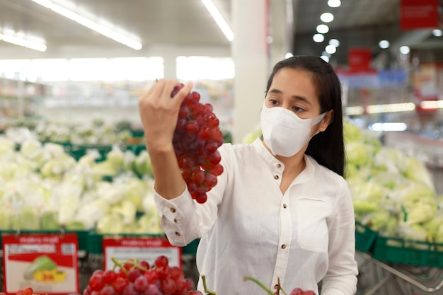 Femme asiatique cheveux longs portant un masque protecteur dans le grand magasin de supermarché