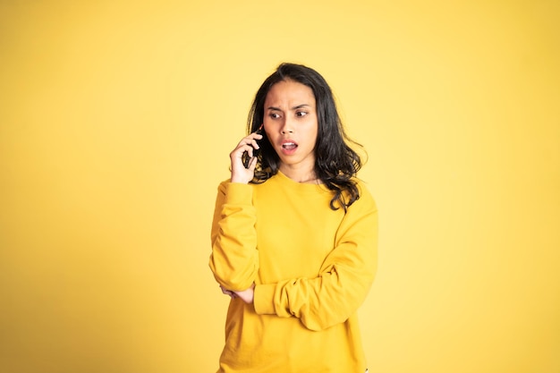 Femme asiatique choquée passant un appel à l'aide d'un téléphone portable