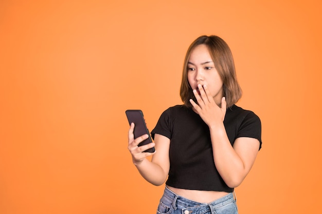 Femme asiatique choquée en regardant son téléphone portable