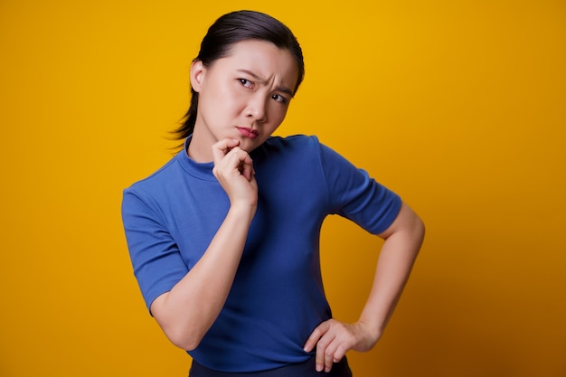 Femme asiatique confuse pensant et debout sur le jaune.