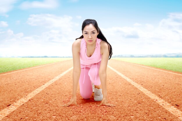 Femme asiatique coureuse prête à courir sur la piste de course à pied