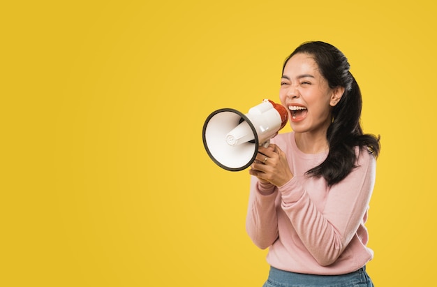 Femme asiatique criant tout en tenant un mégaphone à deux mains faisant une annonce