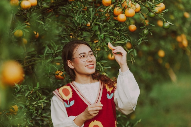 Femme asiatique cueillant joyeusement des oranges dans le jardin