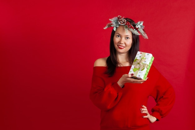 Femme asiatique dans une couronne de Noël tenant une boîte cadeau verte