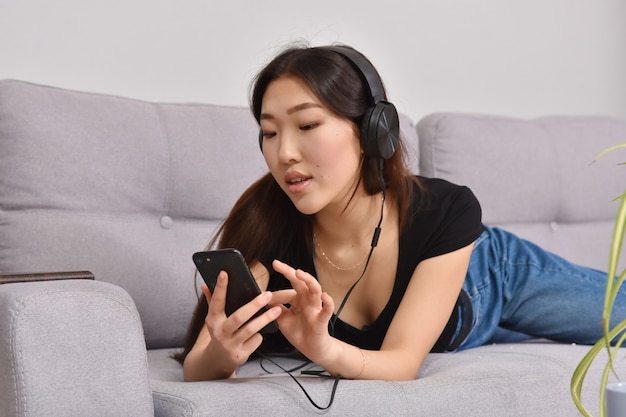 Femme asiatique, dans, écouteurs, utilisation, smartphone