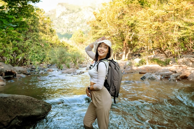 Photo une femme asiatique dans une robe d'été éclabousse dans l'eau à une cascade qui descend du flanc d'une montagne