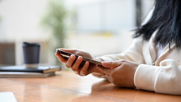 Une femme asiatique dans des vêtements confortables à l'aide de son smartphone à son bureau