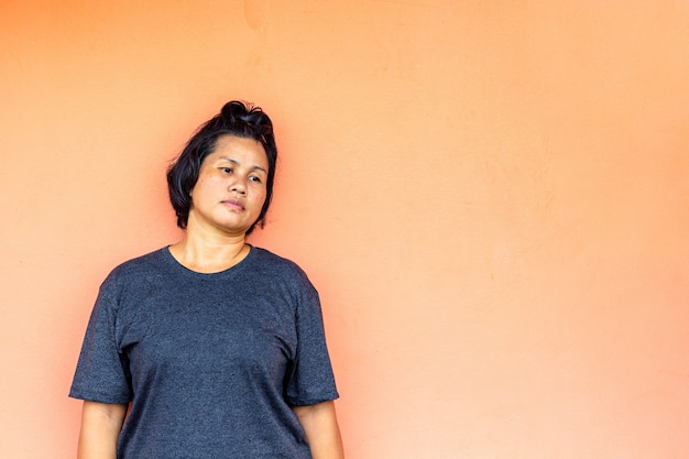 Femme asiatique debout avec mur orange.