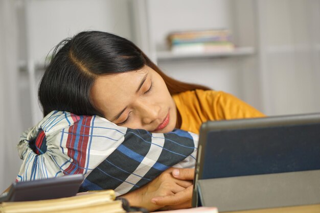 Une femme asiatique dormant sur son bureau à la maison.