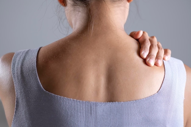 Une femme asiatique a des douleurs à l'épaule Femme tenant une épaule douloureuse avec une autre main Personnes ayant un problème de muscles corporels