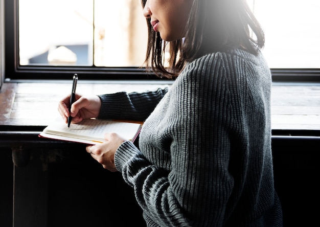 Femme asiatique écrivant sur un cahier