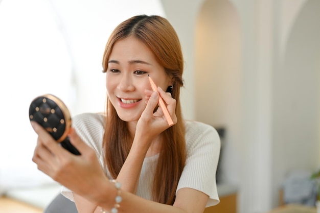 Femme asiatique élégante ou blogueuse beauté féminine se maquillant à l'aide d'un eye-liner