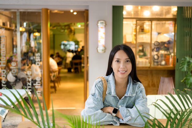 Une femme asiatique est assise à l'intérieur du café.