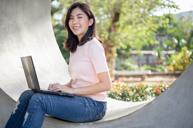 Une femme asiatique est assise sur un ordinateur portable.