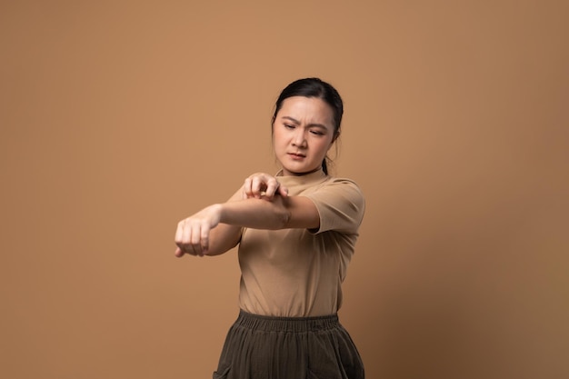 Femme asiatique était malade avec des démangeaisons irritées sa peau se grattant la peau debout isolé sur fond beige