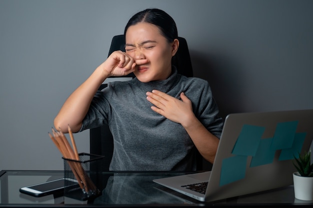 Femme asiatique était malade de fièvre, travaillant sur un ordinateur portable au bureau