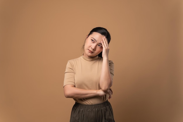 Une femme asiatique était malade de maux de tête touchant sa tête et debout isolée sur fond beige