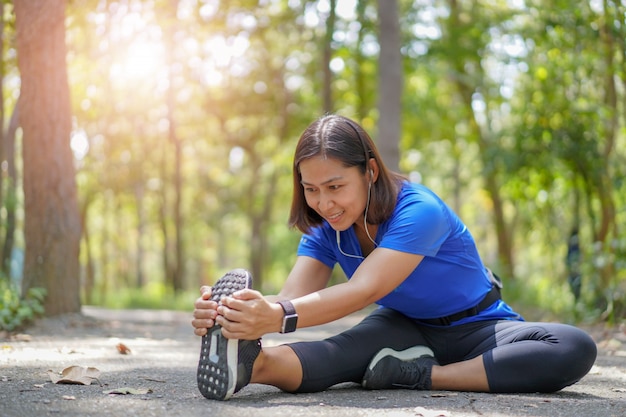 Femme asiatique, étirer, muscles, à, parc, et, écouter musique