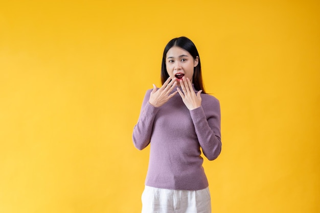 Une femme asiatique étonnée et joyeuse couvre sa bouche en disant wow