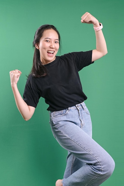 Une femme asiatique excitée célèbre la victoire sur un fond vert.