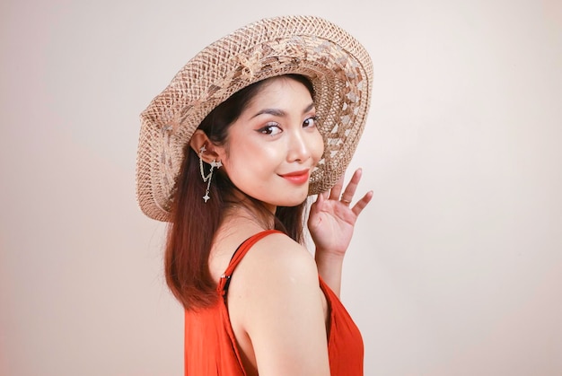 Femme asiatique excitée en chapeau de paille ayant des vacances à la plage isolée sur fond de studio blanc