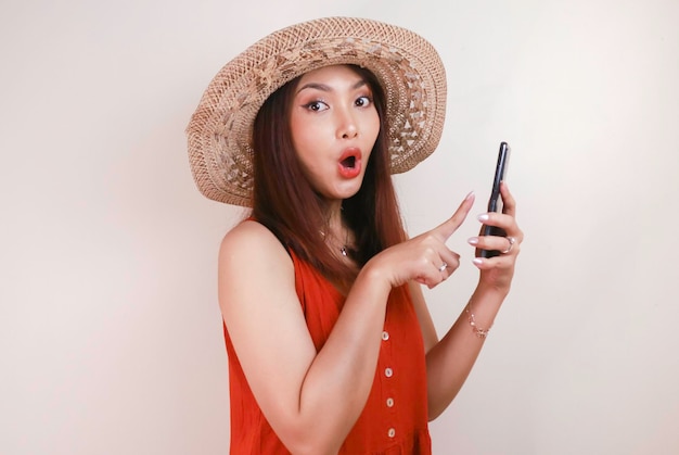 Femme asiatique excitée et choquée pointant le doigt sur un smartphone dans sa main