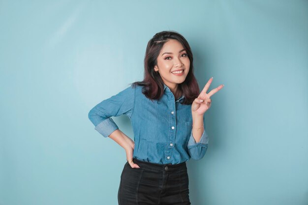 Femme asiatique excitée portant une chemise bleue donnant le numéro 12345 par geste de la main