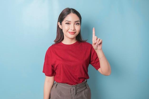 Femme asiatique excitée portant un t-shirt rouge donnant le numéro 12345 par geste de la main