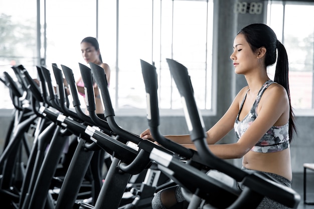 Femme asiatique exerce avec le cardio dans la salle de gym.