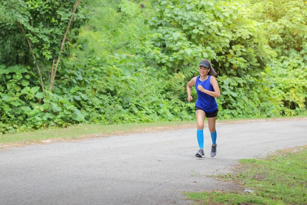 Femme asiatique faisait du jogging sur la route Dans la forêt.