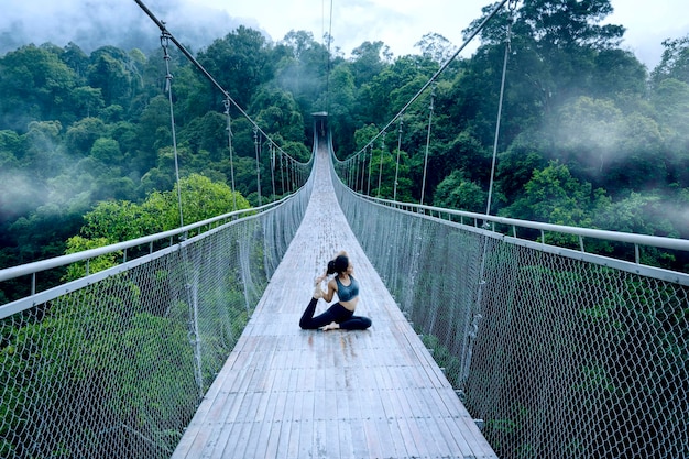 Une femme asiatique faisant du yoga sur le pont.