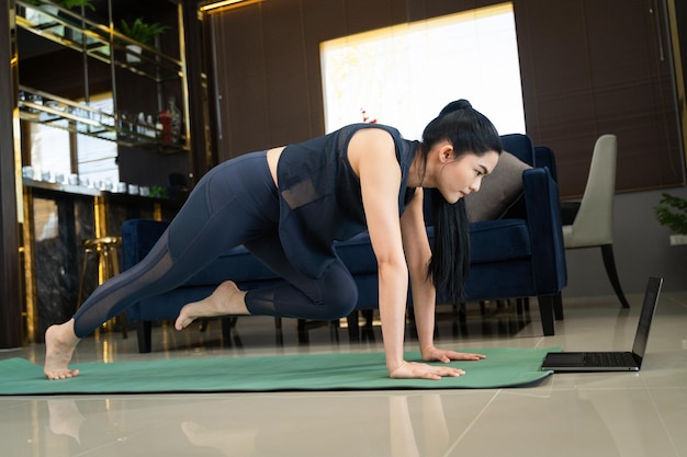 Une femme asiatique fait de l'exercice physique en ligne à la maison
