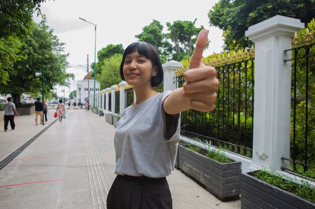 Une femme asiatique fait un geste du pouce dans les espaces publics