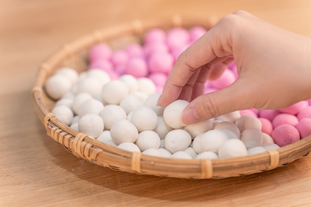 Une femme asiatique fait Tang yuan, yuan xiao, boulettes de riz de la cuisine traditionnelle chinoise en rouge et blanc pour le nouvel an lunaire, festival d'hiver, gros plan.