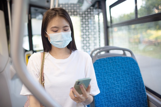 Une femme asiatique fait un tour dans le bus ou le tram des transports publics.