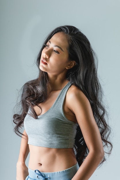 Photo femme asiatique avec des formes galbées sexy posant dans un look branché le corps de la fille athlétique sur un fond